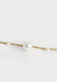 Bracciale in oro con tre perle bianche di dimensioni diverse, intervallate da piccoli gemme chiare lungo la catena.