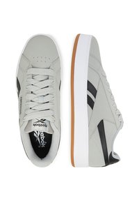 Szare sportowe sneakersy z gładką cholewką, czarnymi akcentami, białą podeszwą i teksturowanym sznurówkami. Posiadają wyściełany kołnierz i perforowane wzornictwo w okolicy palców.