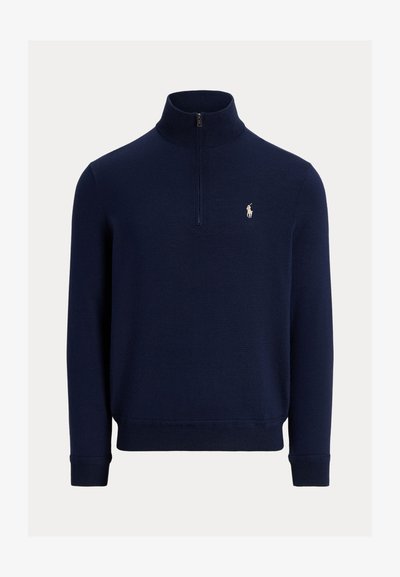 Tamsiai mėlynas ilgarankovis megztinis su ketvirčio užtrauktuku, su įriebalinta apykakle, rankogaliais ir apačia, taip pat su mažu baltais išsiuvinėtu polo žaidėjo logotipu kairėje krūtinės pusėje.