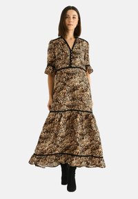 Leopard print maxi dress with short sleeves, black trim, and frilled hem. Fabric appears lightweight and textured. Worn with black knee-high boots.