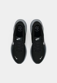 Sneaker nere Nike con accenti grigi, upper in rete, punta rotonda, soletta imbottita e logo bianco prominente su ogni scarpa.