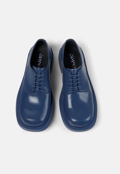 Blauwe leren veterschoenen met een gladde afwerking, ronde neus en contrasterende rood-blauwe patroon binnenzolen. Close-up van bovenaf.