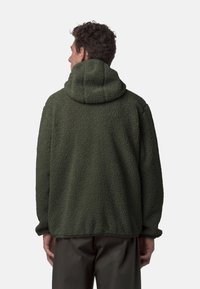 Giacca in pile verde scuro, con colletto alto e superficie testurizzata. Vestibilità ampia con polsini e orlo elasticizzati, maniche lunghe.