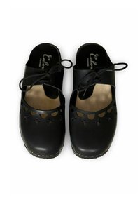 Zwarte leren schoenen met open zijkanten, uitgesneden bloemenpatronen aan de voorkant en vetersluiting. Houten inlegzool zichtbaar.