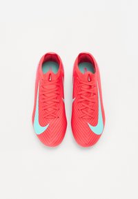 Red athletic shoes with a textured surface, featuring a large light blue Nike logo, traditional lacing, and a cushioned insole.