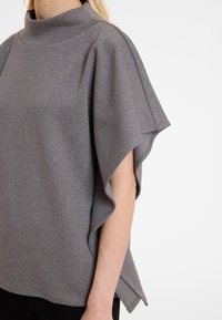 Grijze top met verticale strepen, korte mouwen en een hoge kraag. Gemaakt van zachte stof met een subtiele glans en een vloeiende silhoeet.