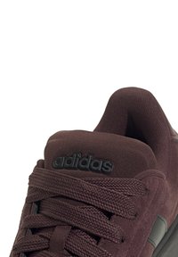 Baskets bordeaux avec une tige texturée, dotées de lacets épais et d'un logo "adidas" noir sur la languette. Tissu doux et col rembourré.