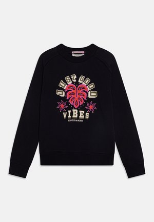 Zwarte sweat met lange mouwen met de tekst "JUST GOOD VIBES", roze en rode tropische blad- en bloemontwerpen en Scotch & Soda-logo aan de voorkant.