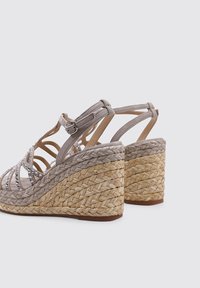 Sandalias de cuña de ante gris con tacón de yute trenzado, que presentan correas decorativas y acentos de strass. Cierre ajustable con hebilla en el tobillo.