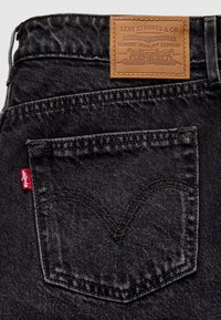 Μαύρα τζιν από denim με δερμάτινη ετικέτα στη μέση με ανάγλυφο λογότυπο και κόκκινη ταμπέλα στην πίσω τσέπη. Ορατή κλασική ραφή.