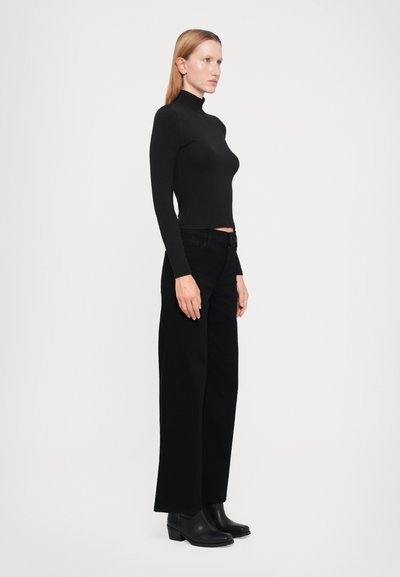 Svart mock turtleneck topp i kombination med högmidjade svarta vida jeans och svarta ankelboots. Slät textur, åtsittande topp och rena linjer.