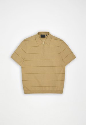 Μπεζ κοντομάνικο πόλο μπλουζάκι με λεπτές οριζόντιες ρίγες και γιακά με φερμουάρ μπροστά σε λευκό φόντο.