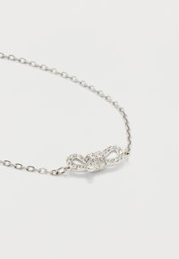 Ασημένιο κολιέ αλυσίδας με διακοσμητικό κούμπωμα σε σχήμα φιόγκου, διακοσμημένο με μικρούς διαφανείς κρυστάλλους πάνω σε άσπρο φόντο.