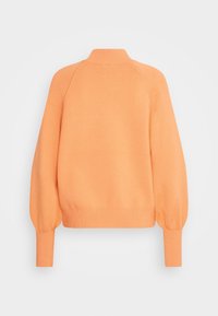 Jersey naranja de punto con un cuello alto, mangas raglán y puños acanalados; presenta una textura suave y una silueta ligeramente recortada.