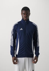 Marineblå glidelås treningsjakke med hvite side-striper og Adidas-logo. Glatt tekstur, atletisk passform, ståkrave og ribbestrikkede mansjetter.