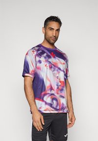 Tricou sport cu mânecă scurtă în culoare mov, cu un model abstract vibrant în roz și roșu, cu decolteu rotund și detaliu cu logo pe mânecă.