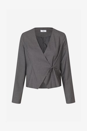 Pelēks svītrainais garroku kultivētais žakets ar pārklājošu priekšpusi, sasaistīts sānos, un melna iekšējā oderējuma detaļa redzama pie apkakles.