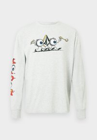 T-shirt grigia a maniche lunghe in cotone con un grafico centrale che presenta personaggi dei cartoni animati con grandi occhi, e dei design colorati su entrambe le maniche.