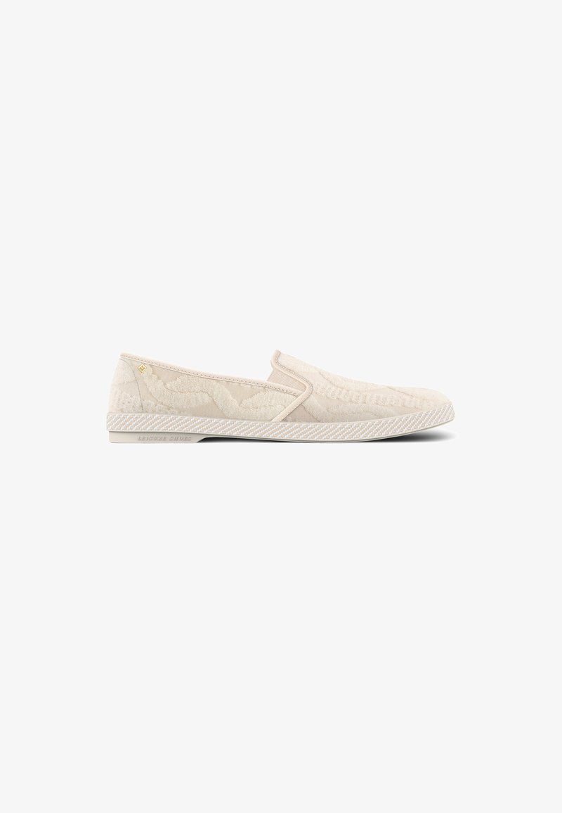 Cream-colored slip-on shoes with textured fabric upper and contrasting striped sole. Features subtle branding on the side.