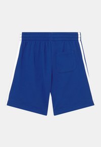Pantalones cortos deportivos azules con una cintura elástica, rayas blancas a los lados y un solo bolsillo trasero en el lado derecho.