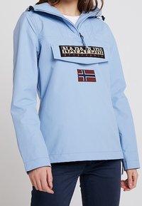 Jasny niebieski polarowy kurtka z przednią kieszenią, regulowanym kapturem i haftowanym detalem w postaci norweskiej flagi. Wykonana z materiału wodoodpornego.