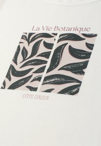 Motif de feuilles botaniques en deux panneaux avec le texte « La Vie Botanique » en haut et « Côte d'Azur » en bas sur tissu blanc.