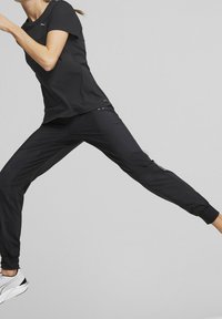 Svart sportkläder som består av en kortärmad topp och tajta byxor, båda gjorda av lätt material med subtila reflektiva accenter.