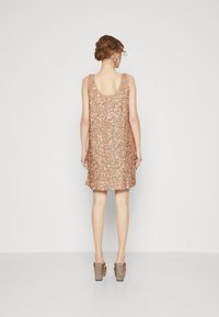 Roze gouden paillettenjurk met een ronde rug, aansluitend ontwerp, lengte tot halverwege de bovenbenen, gecombineerd met gestructureerde blokhakken.