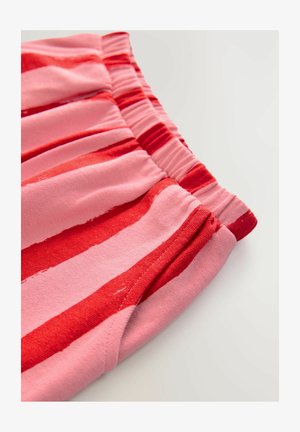 Červená a ružová pruhovaná látka s elastickým pásom, ktorá má jemnú textúru a jemný lesk. Pruhy sa líšia šírkou.