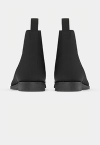 Botas negras hasta el tobillo con una textura suave, tacón bajo apilado, paneles laterales elásticos y un diseño minimalista.