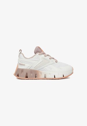 Bílá a béžová teniska Reebok s síťovanými panely, šněrováním a silnou texturovanou podrážkou, zobrazená ze strany na jednoduchém pozadí.