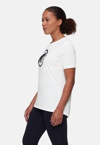 Biała bawełniana koszulka z krótkim rękawem, z czarnym graficznym wzorem przedstawiającym zwierzę na przodzie. Okrągły dekolt, luźny krój.