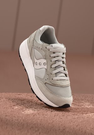 Gray sneaker with a mix of suede and mesh materials, featuring a white logo, lace-up design, and a textured sole.