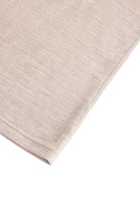 Világos bézs színű szövetnégyzet, puha, texturált felülettel. Finom varrás és egy kis logórészlet látható a sarkában.