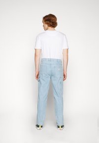 Light blue denim cargo pants with a relaxed fit, featuring multiple pockets and a high waistband, paired with a plain white t-shirt.