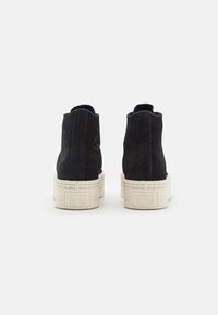 Black suede high-top shoes with a ribbed white platform sole. Features a logo embossed on the back and a smooth textile finish.