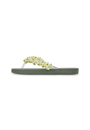 Tongs vertes à semelle plate, ornées de décorations de fleurs blanches et jaunes ainsi que de petites perles vertes sur les brides.