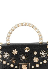 Black textured handbag with a pearl-accented handle, adorned with decorative gold and pearl embellishments, featuring floral and insect motifs.
