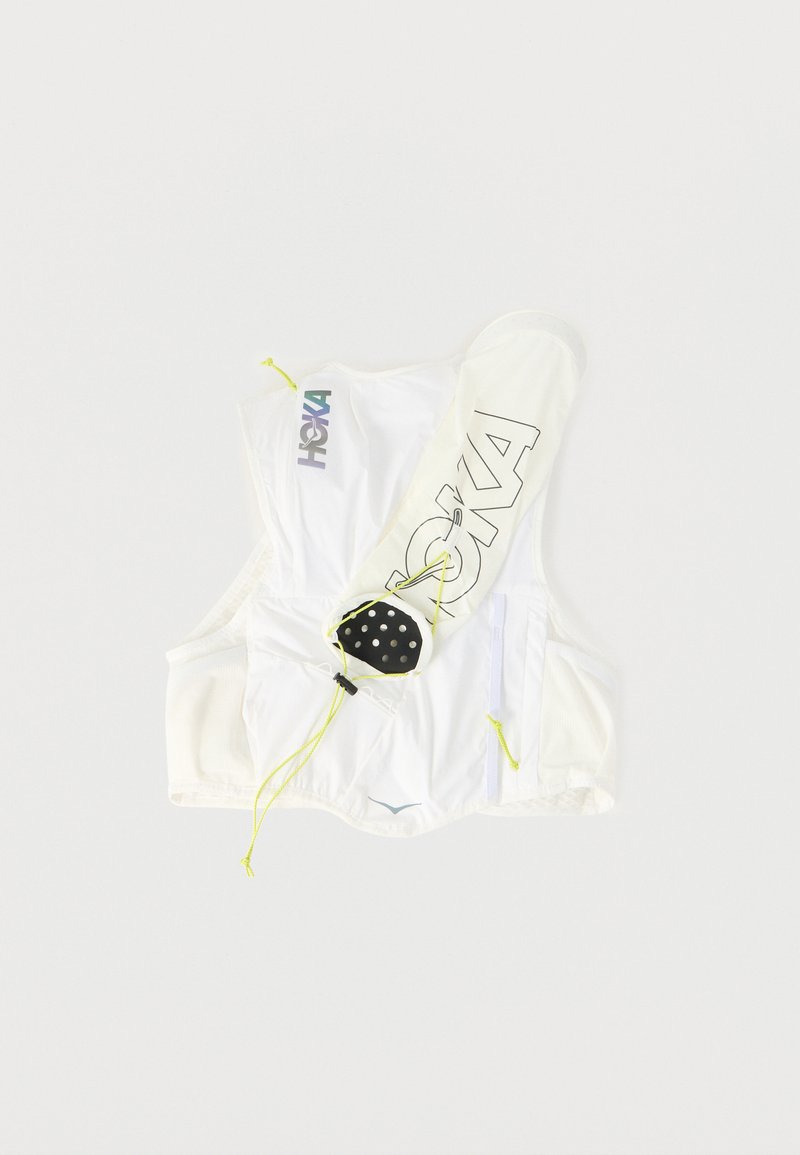 Gilet idratante bianco con marchio HOKA, dotato di cinghie regolabili e una piccola tasca nera attaccata, posato su uno sfondo bianco.