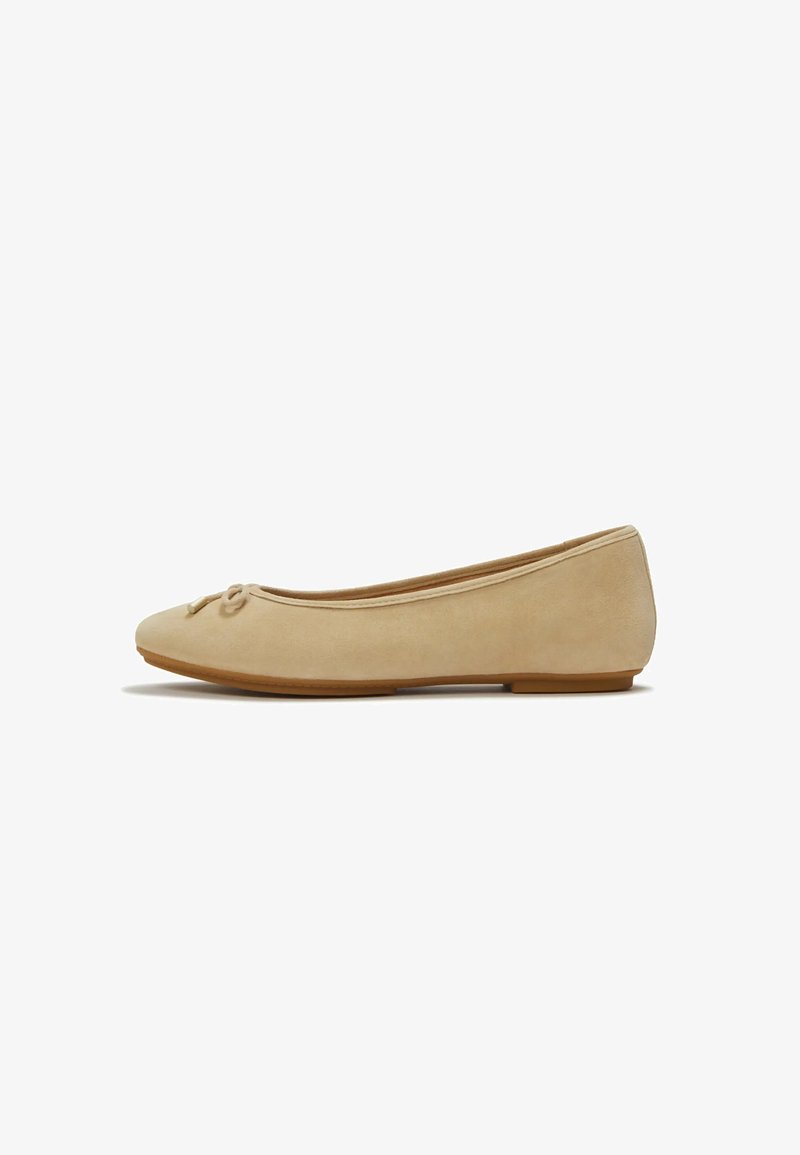 Scarpa ballerina piatta in camoscio beige con punta arrotondata, piccolo dettaglio con fiocco e suola piatta in gomma, mostrata di profilo.