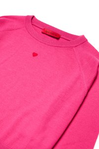 Rosa genser laget av mykt materiale; har rund hals og ribbede mansjetter. Merkelig detalj: et lite rødt hjerte brodert på brystet.
