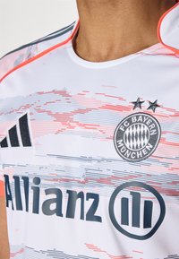 Maglietta bianca del FC Bayern München con strisce orizzontali grigie e rosa, logo Adidas e testo dello sponsor "Allianz" in grigio scuro.