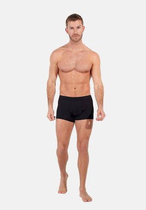 Black boxer briefs on a model, made from a smooth, stretchy fabric. Minimalist design with a soft waistband, no visible branding or patterns.