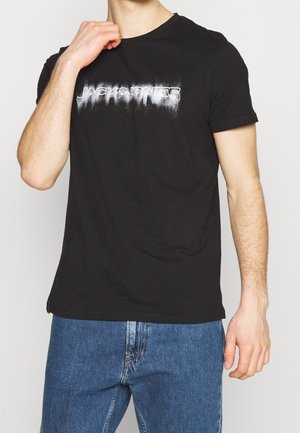 T-shirt en coton noir avec un logo en effet spray blanc "JACK & JONES" sur le devant, col rond, manches courtes et coupe décontractée.