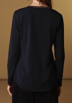 Top de manga larga azul marino con cuello redondeado, que presenta rayas en contraste en el cuello y los puños. Tejido suave y corte relajado.