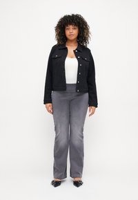 Black denim jacket with front buttons and two chest pockets, paired with gray flared pants. Shoes are black with pointed toes and accents.