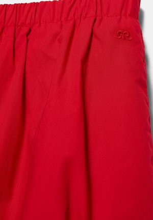 Material roșu cu talie elastică strânsă și un mic logo brodat aproape de colțul din dreapta sus.