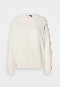 Κρέμα χρώματος φούτερ με στρογγυλή λαιμόκοψη, μακριά μανίκια και μικρό μωβ λογότυπο στο στήθος. Μαλακή υφή υφάσματος με ριμπ ύφανση στις μανσέτες.