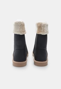 Stivali neri alla caviglia con un colletto in pelliccia sintetica, lati texture e una suola in gomma beige. Presentano un design cucito lungo le cuciture.