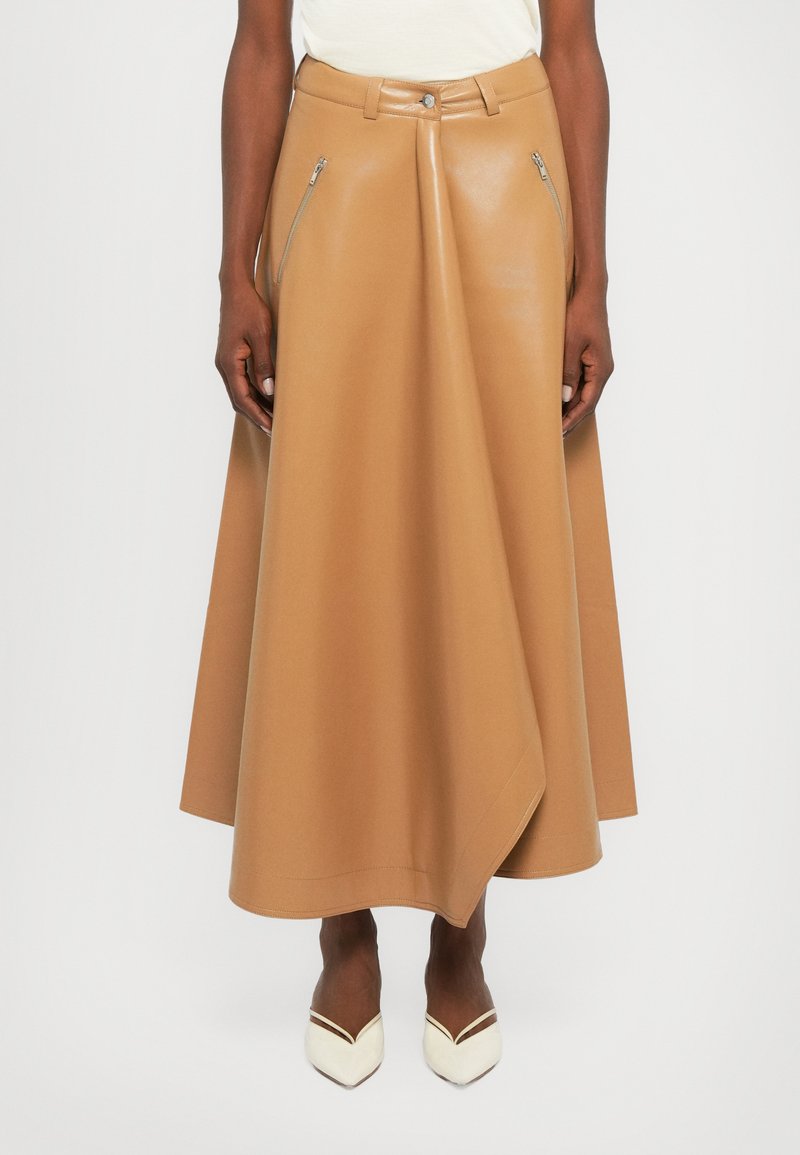 Camelkleurige leren rok met een flared ontwerp, voorzien van zilveren ritsdetails op de voorkant zakken. Soepele textuur en enkel-lange snit.